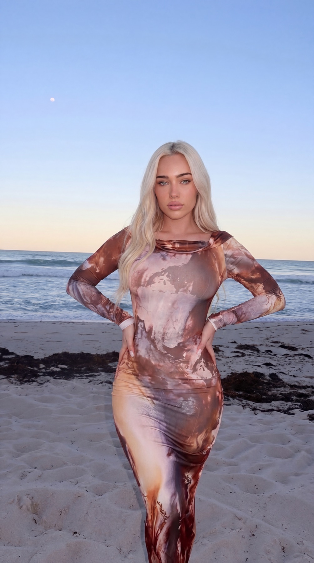 Viper Deme on the beach at sunset in a copper tie-dye maxi dress — Miami creator